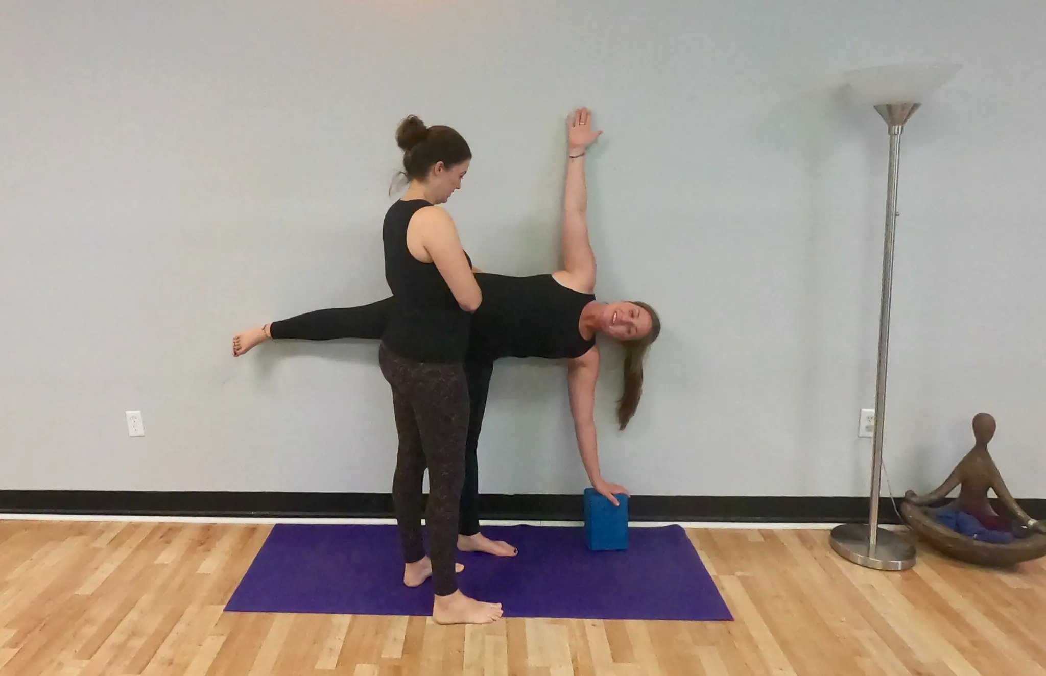 A Palm Yoga teacher giving a hands-on assist in half moon pose