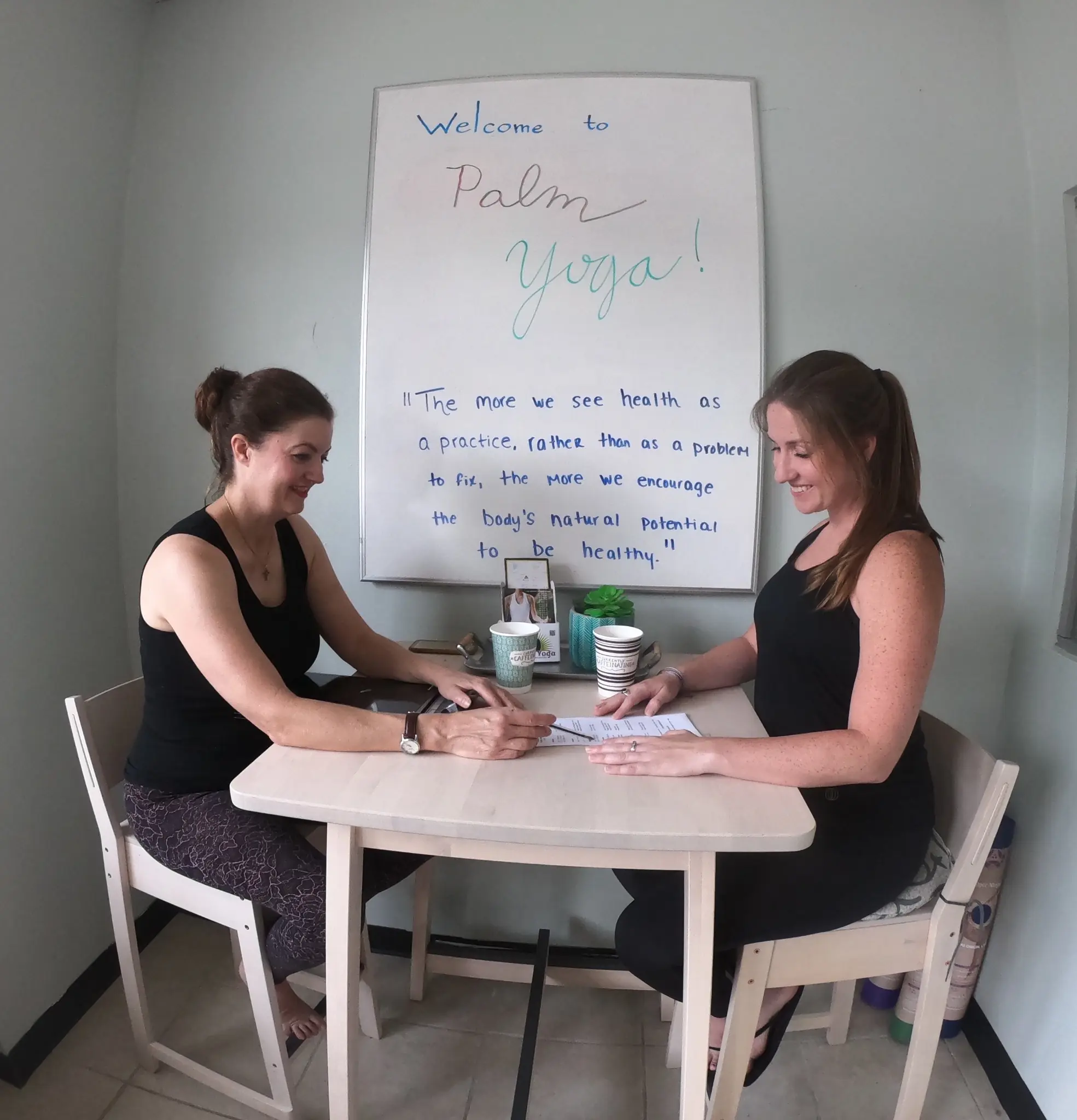 A new student going over class options at the Palm Yoga welcome desk